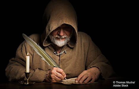 Man sieht einen Mönch bei Kerzenlicht schreiben. Foto: Thomas Mucha/Adobe Stock.