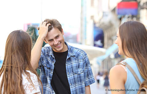 Ein junger Mann flirtet mit zwei jungen Frauen. Foto: Antonioguillem/Adobe Stock.