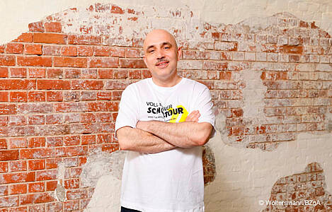 Rap-Teamer Andreas Möckel lächelnd mit verschränkten Armen vor einer Wand. Foto: Woltersmann/BZgA.